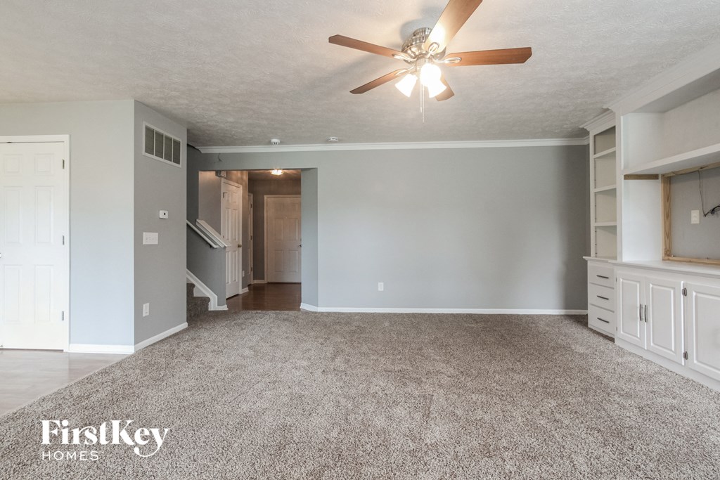 a living room with a carpeted floor and a ceiling fan