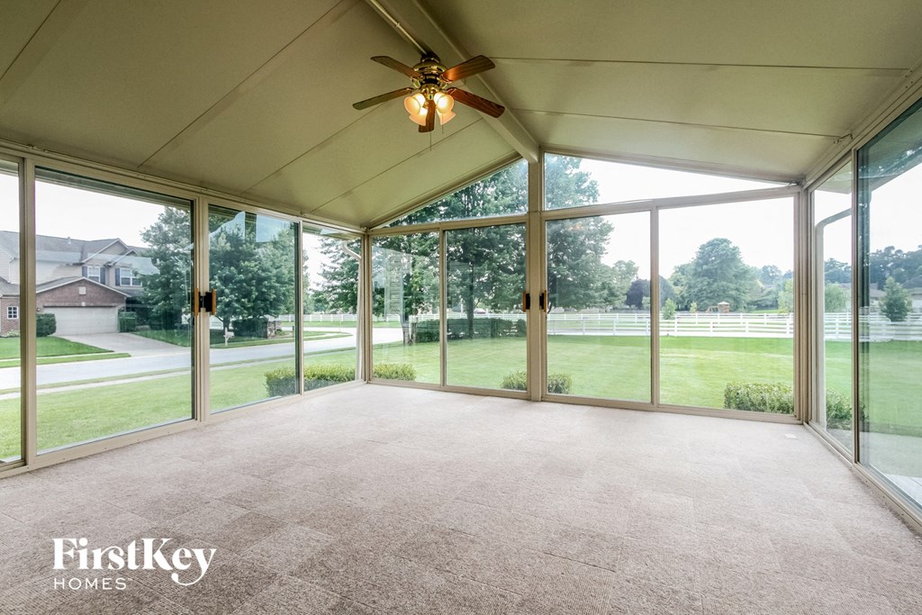 an empty living room with large windows and a ceiling fan