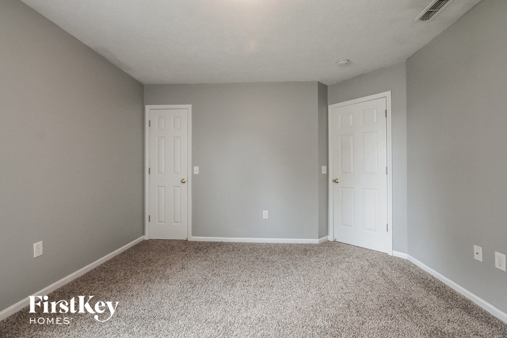a bedroom with two doors and a carpeted floor