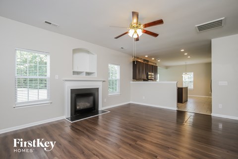 an empty living room with a fireplace and a ceiling fan