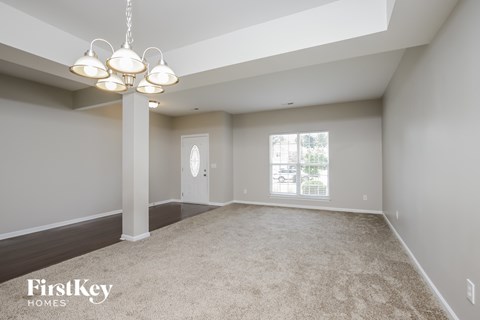 an empty living room with a chandelier and a window