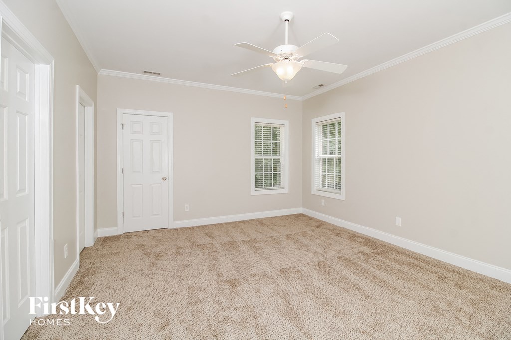 a spacious living room with carpet and a ceiling fan