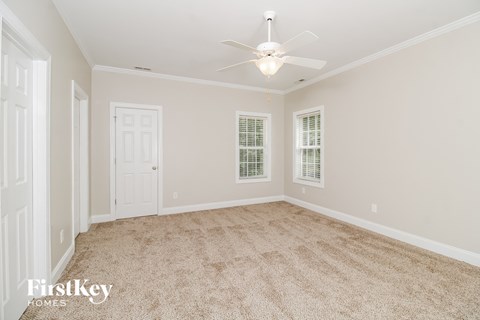 a spacious living room with carpet and a ceiling fan