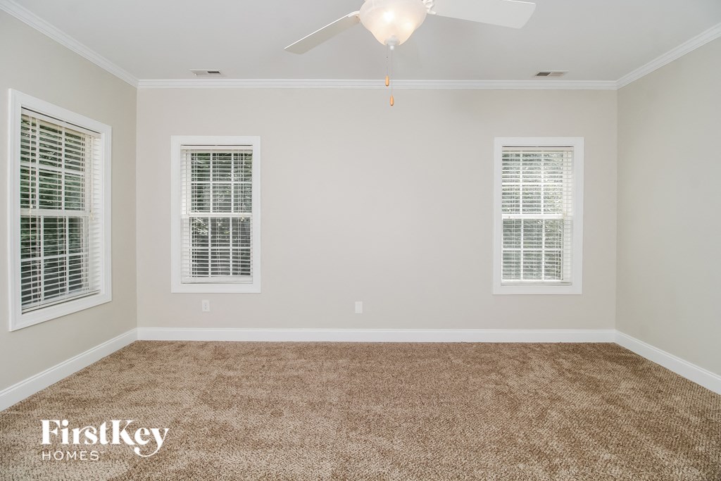 a empty room with a ceiling fan and two windows