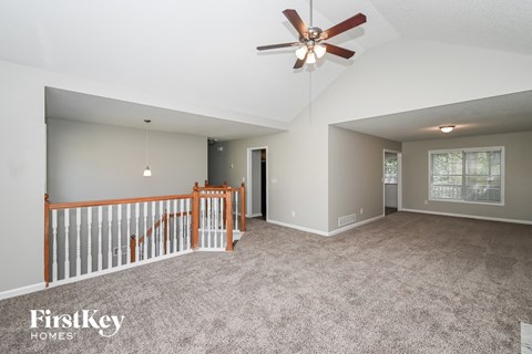 A spacious room with a ceiling fan and a carpeted floor.
