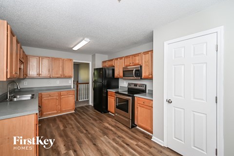 A kitchen with wooden cabinets and a black fridge.