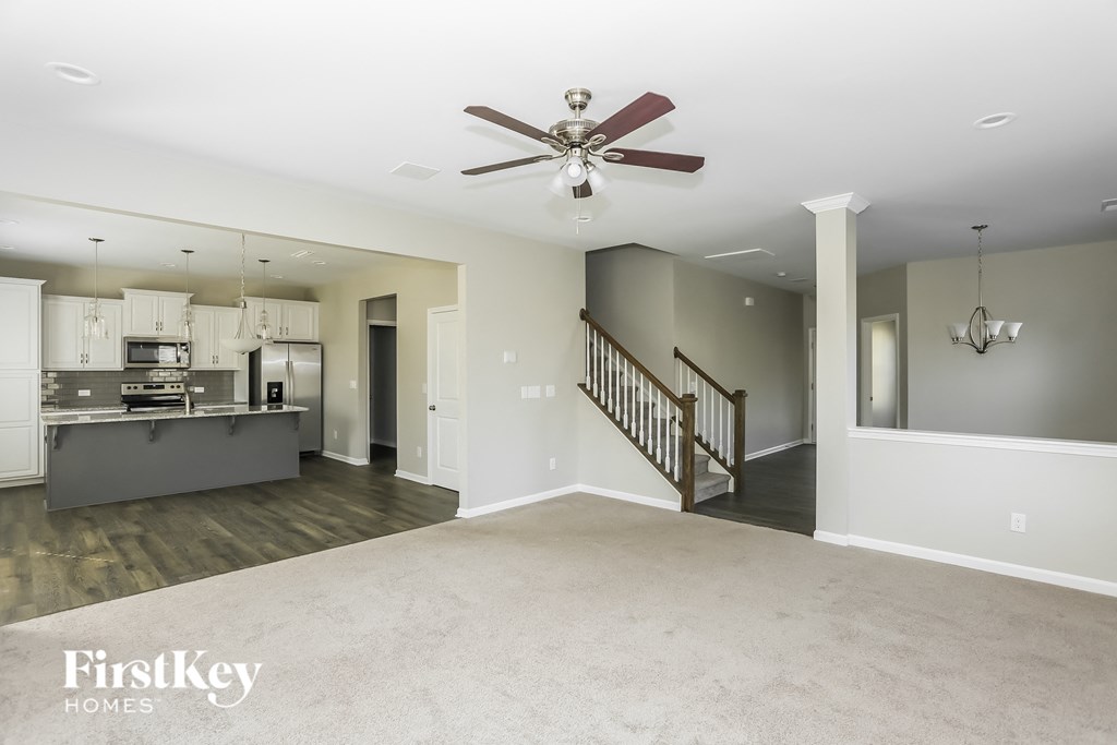an empty living room and kitchen with a ceiling fan