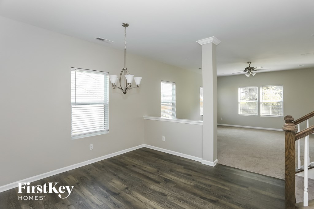 a living room and dining room with white walls and wood floors