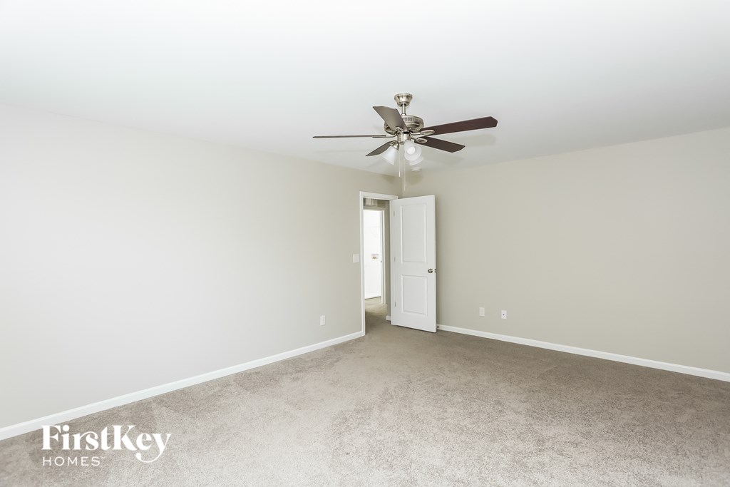 a bedroom with white walls and a ceiling fan