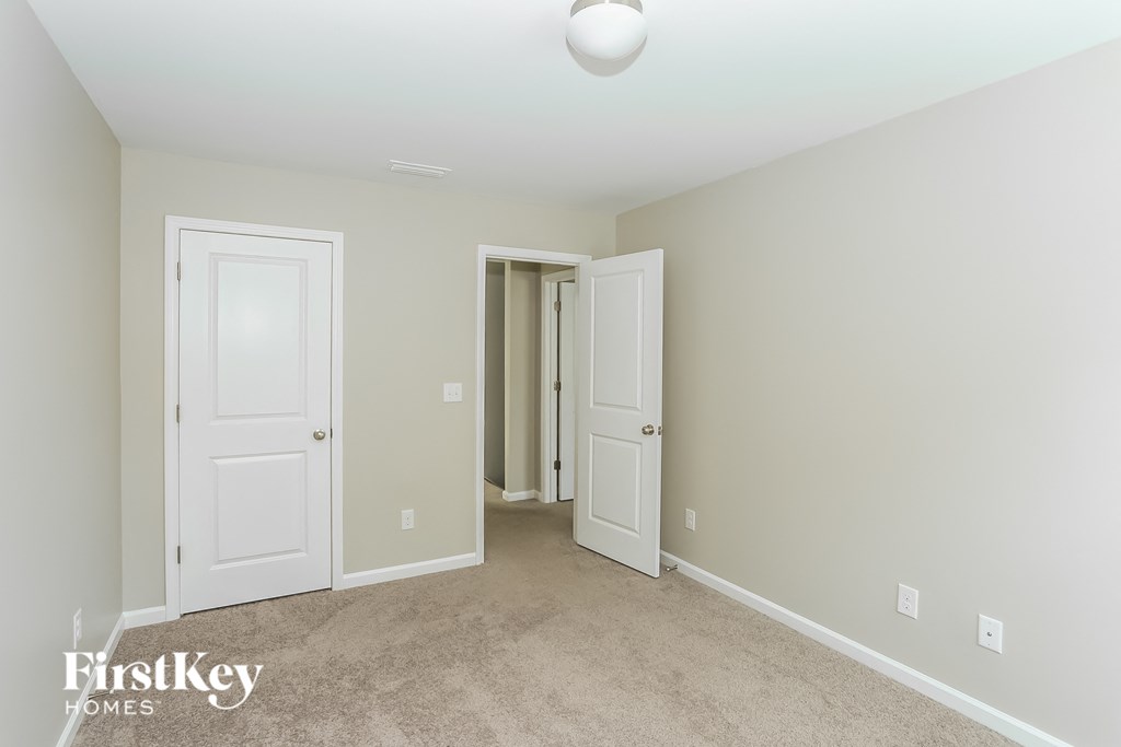 a bedroom with two closets and two doors and a carpeted floor