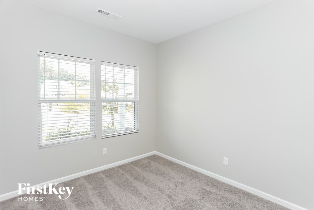 a bedroom with a carpeted floor and two windows