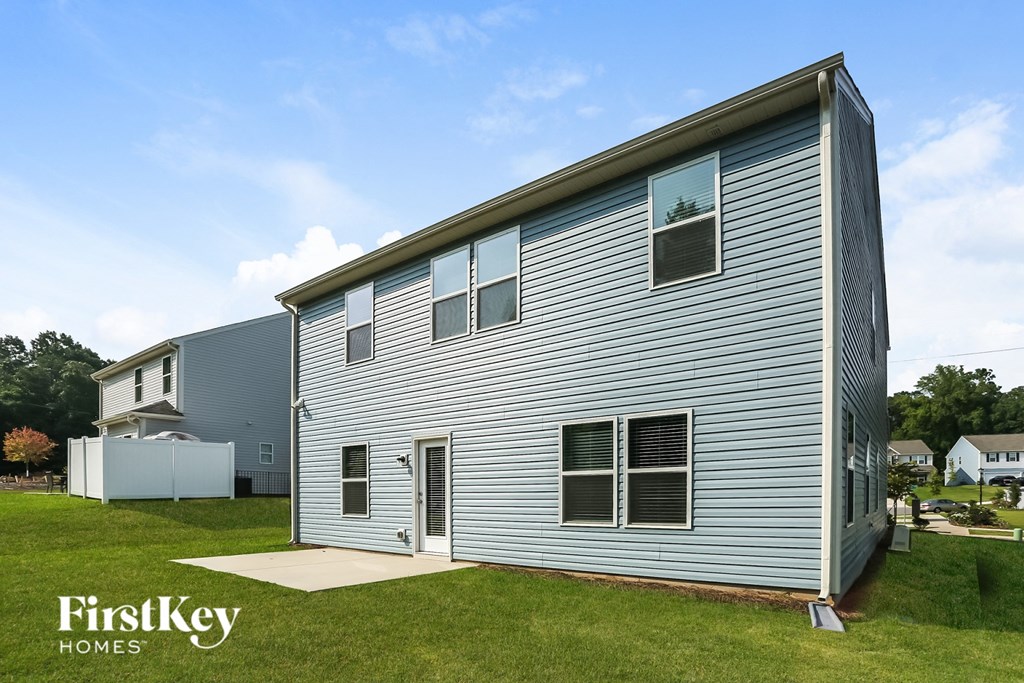 the outside of a house with white siding and a yard with a blue sky