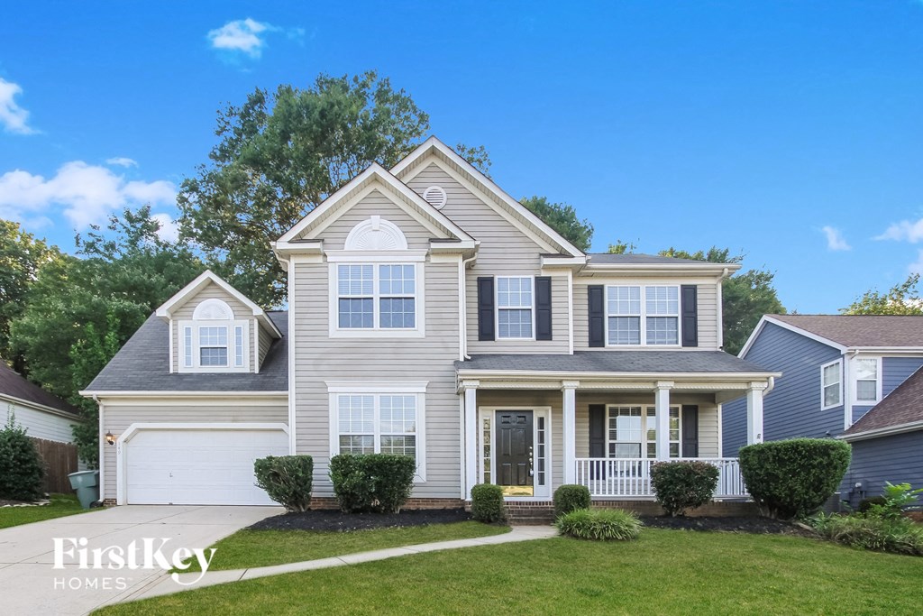 a beige house with white shutters and a lawn