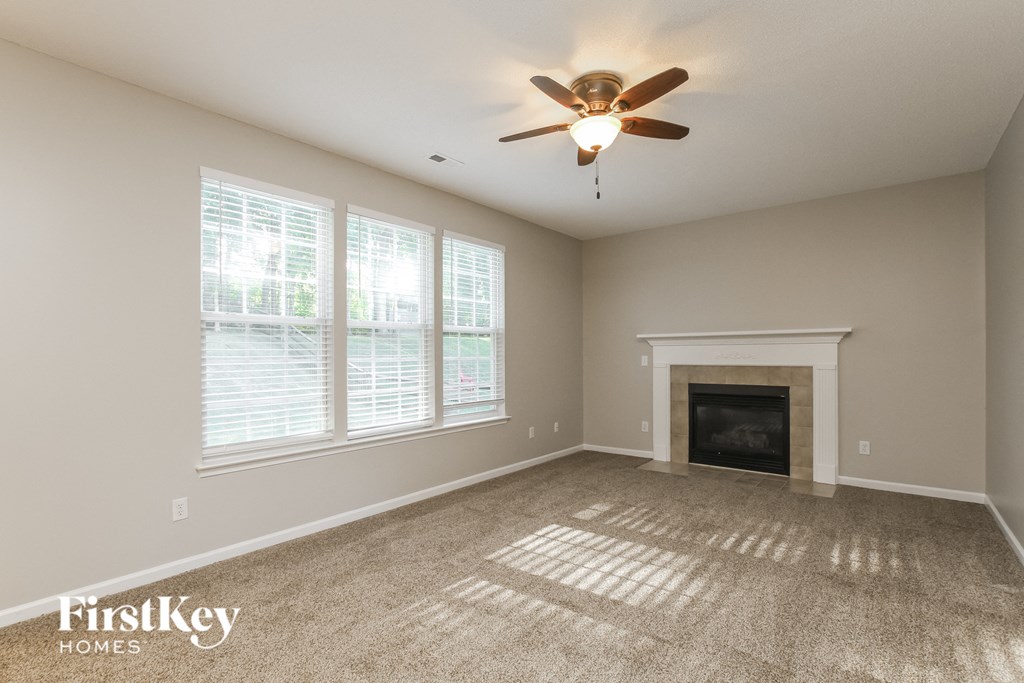 an empty living room with a ceiling fan and a fireplace