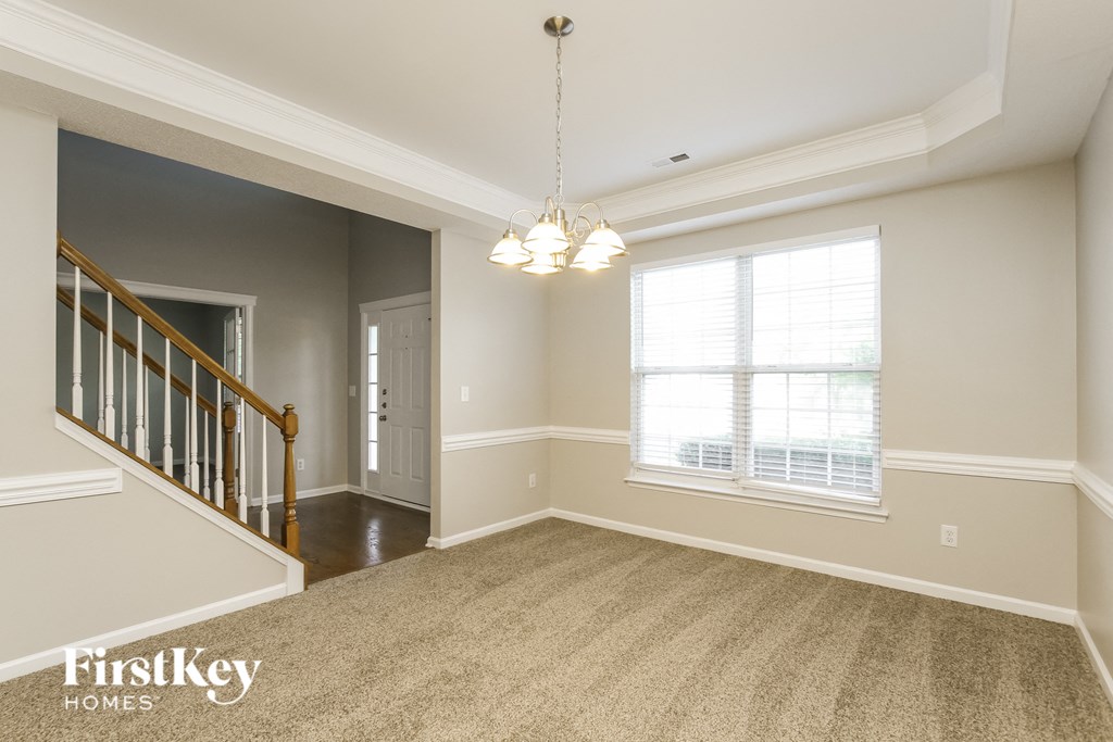 an empty living room with a staircase and a large window