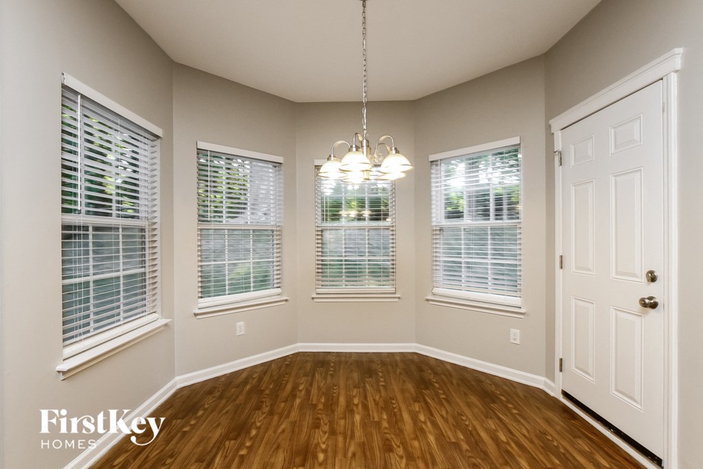 an empty dining room with wood floors and windows