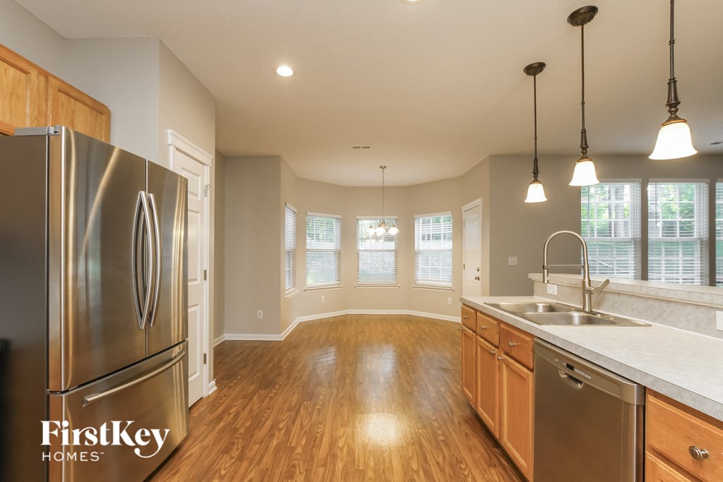 an empty kitchen and dining room with a stainless steel refrigerator