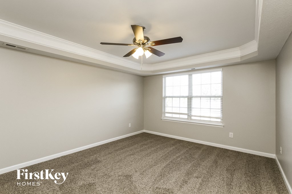 an empty room with a ceiling fan and a window