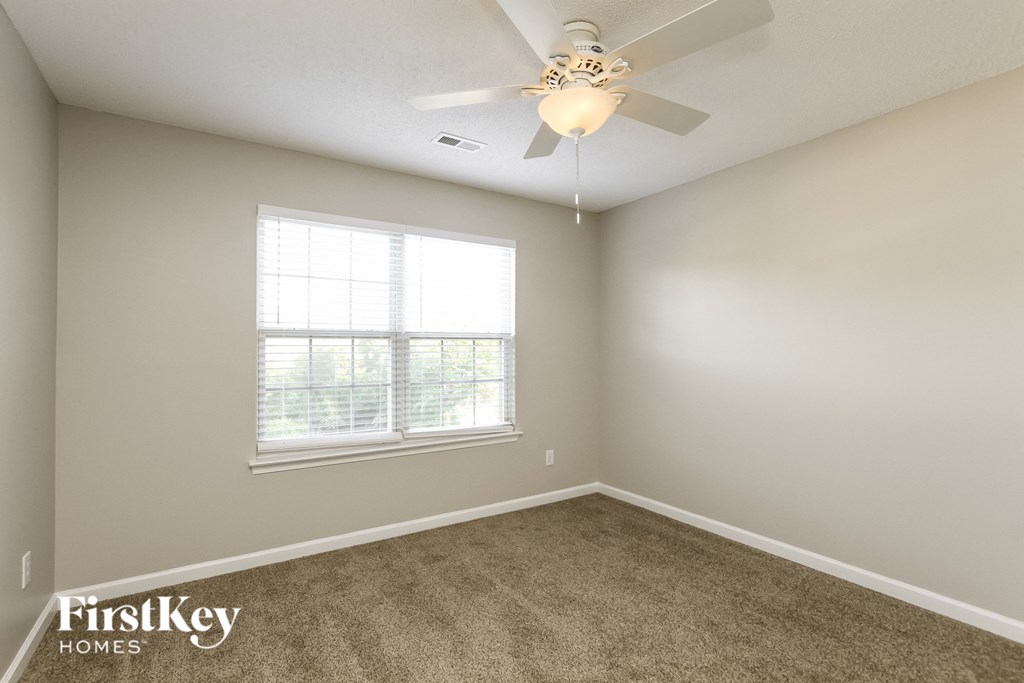 an empty room with a ceiling fan and a window