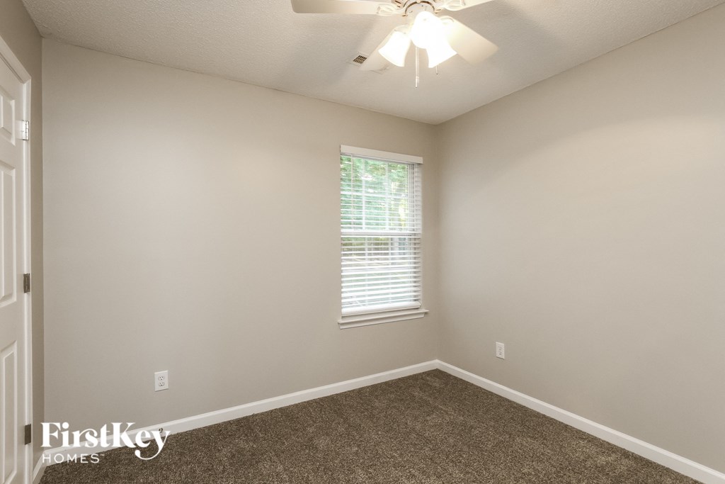a bedroom with carpet and a window and a ceiling fan
