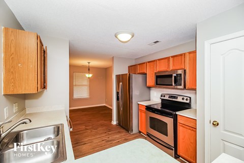 A kitchen with wooden cabinets and a stove top oven.