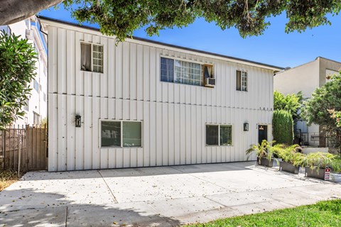A white building with a grey roof and a white fence.