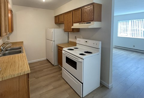 A kitchen with a white stove and refrigerator.