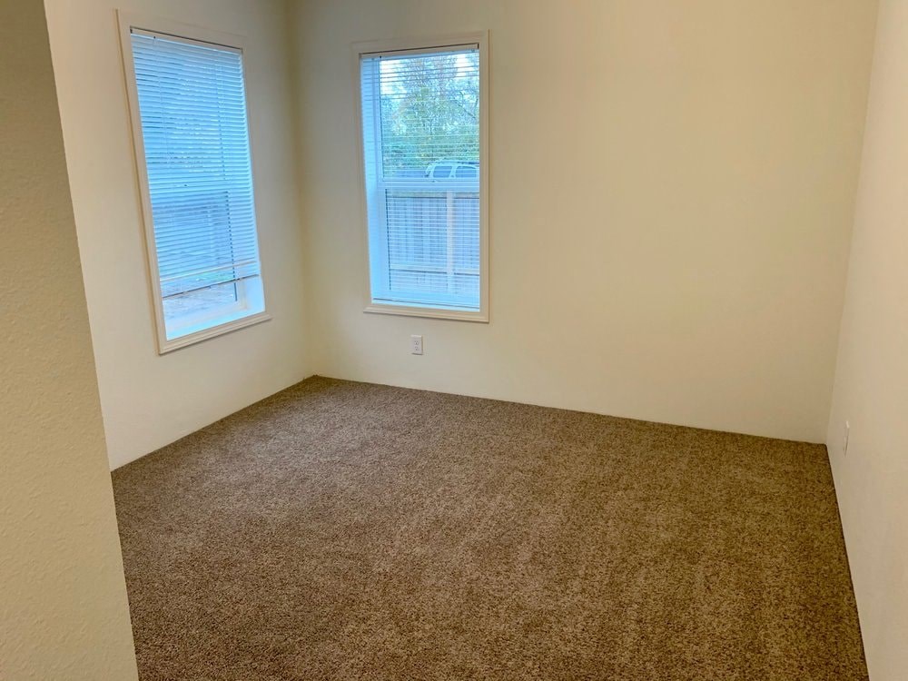 a room with a carpeted floor and two windows