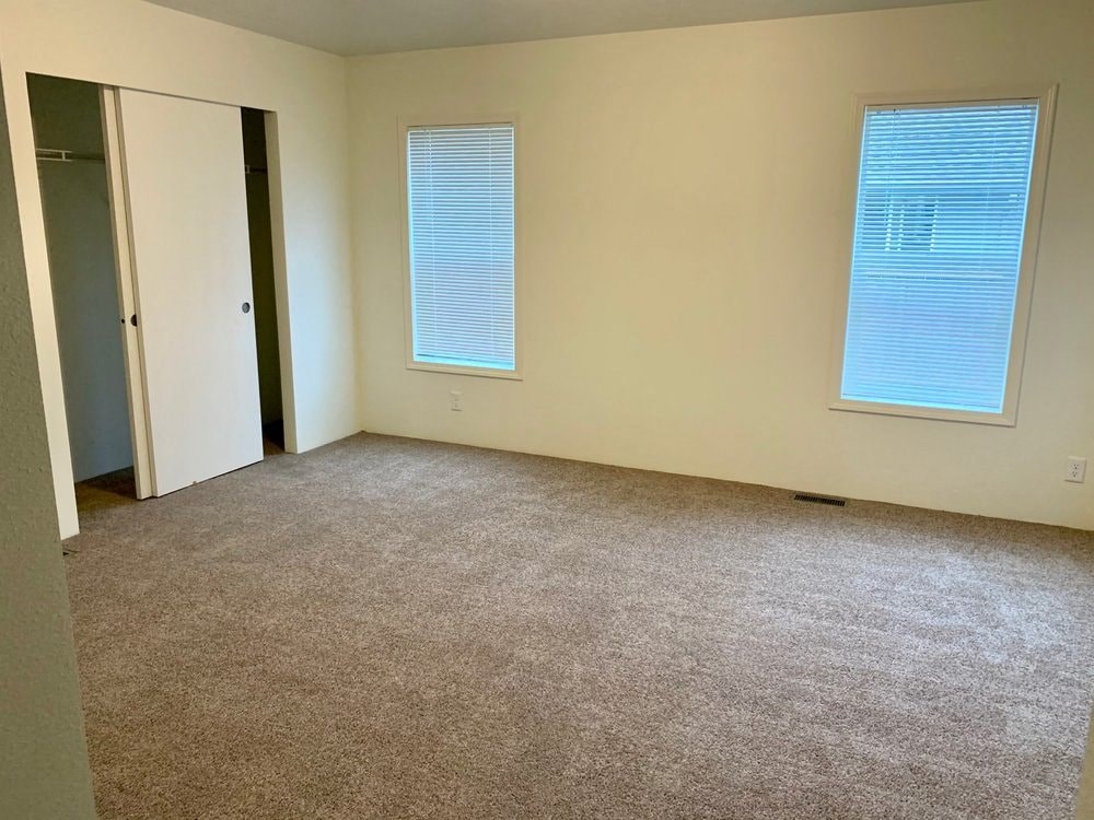 an empty room with a door and two windows