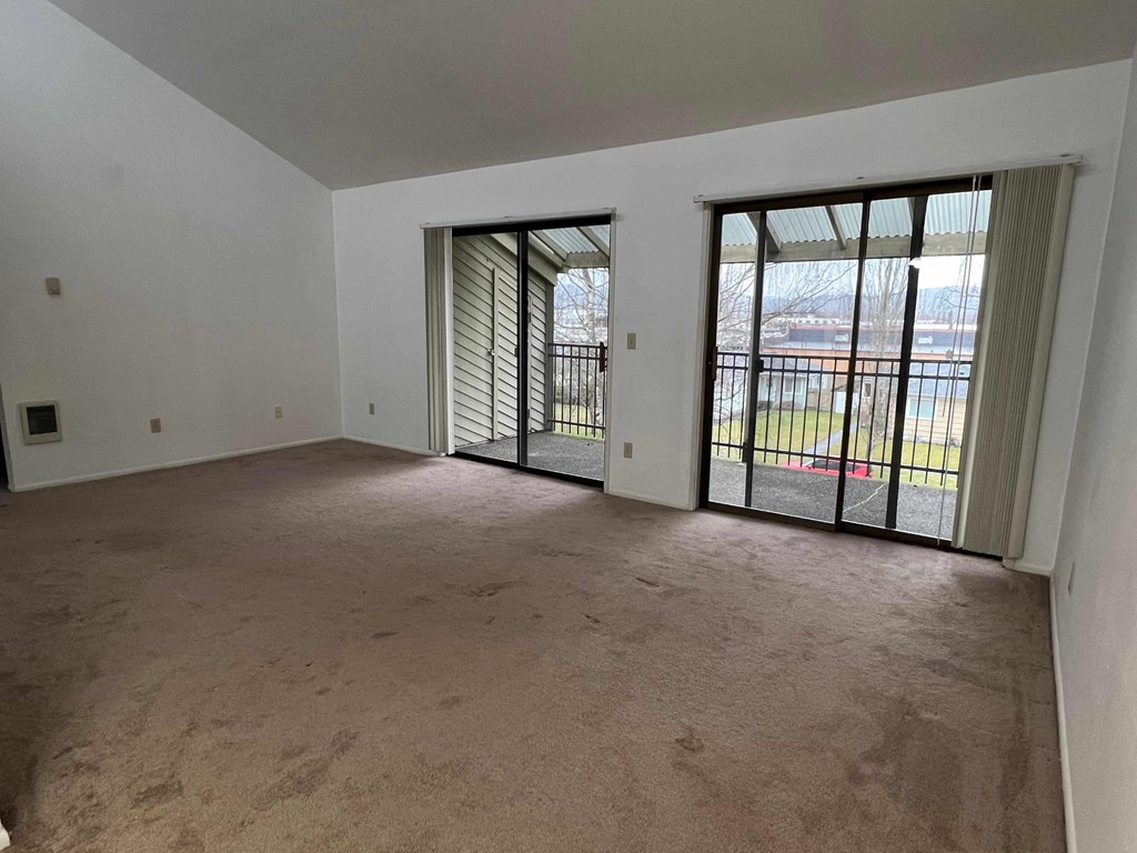 an empty living room with sliding glass doors to a balcony