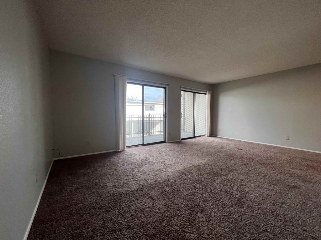 an empty living room with sliding glass doors to a balcony
