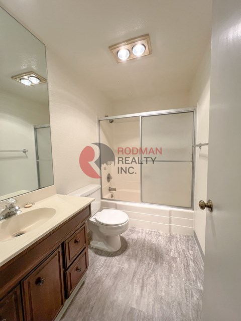 A bathroom with a toilet, sink, and mirror.