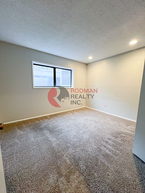 A carpeted room with Rodman Realty Inc. on the wall.