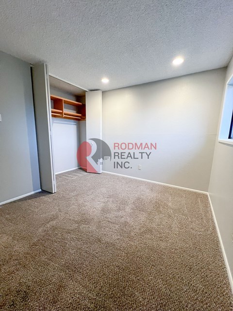 A carpeted room with Rodman Realty Inc. on the wall.