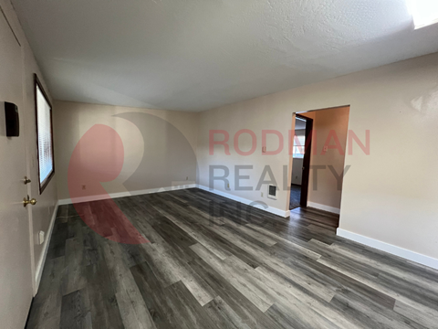 A room with wooden flooring and a doorway leading to another room.