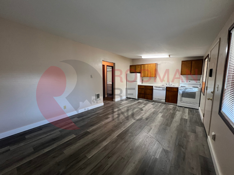 A room with wooden flooring and a white wall with a red circle on it.