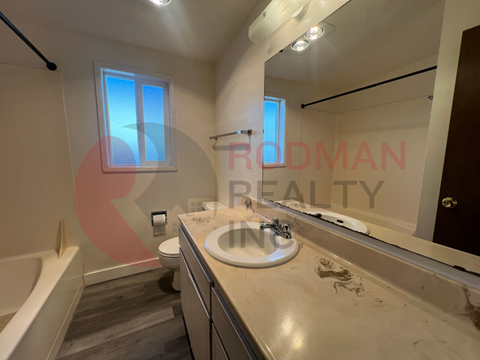 A bathroom with a tub, sink, and mirror.