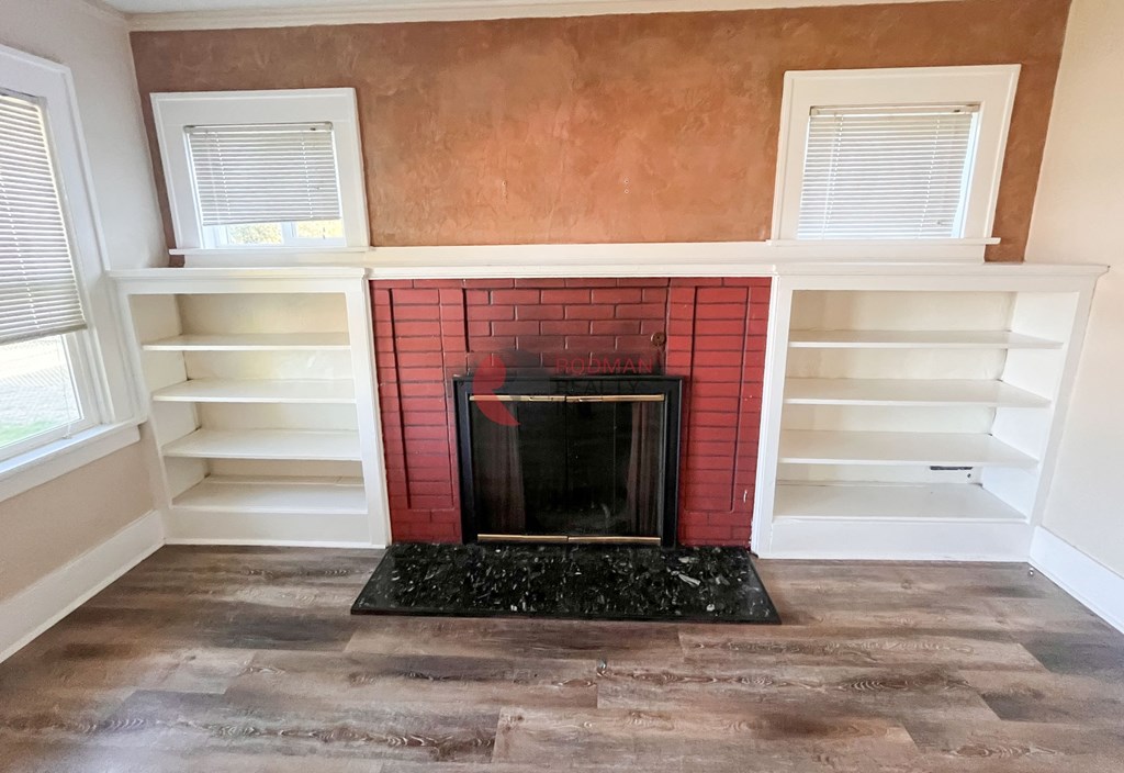 A fireplace with a red brick surround and a black grate in the middle.