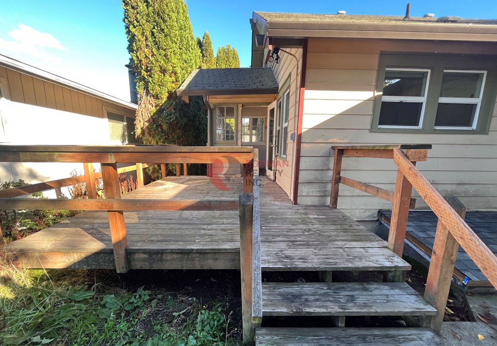 A wooden deck leads to a small house with a porch.