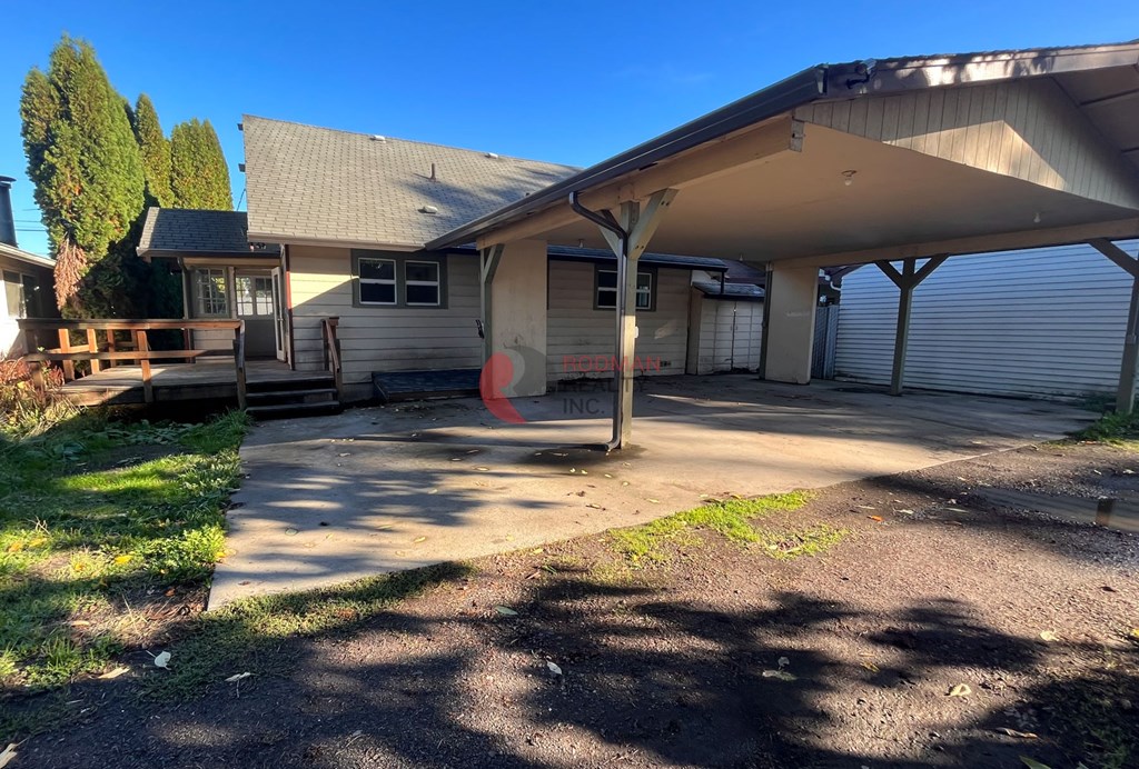 A carport with a garage door is attached to a house.