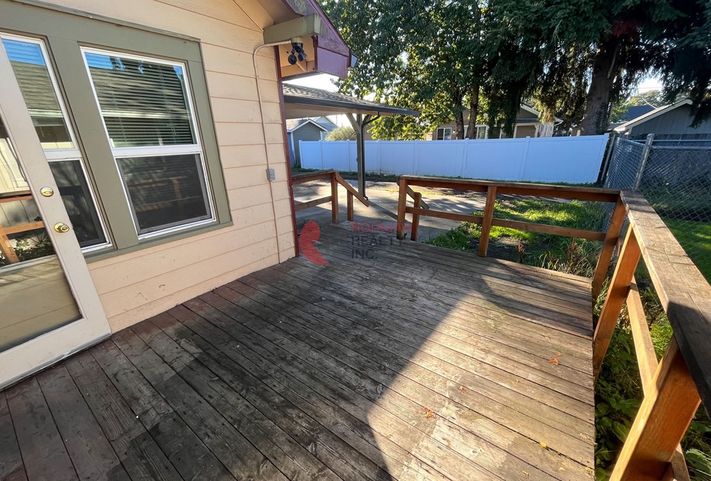 A wooden deck with a bench and a fence in the background.