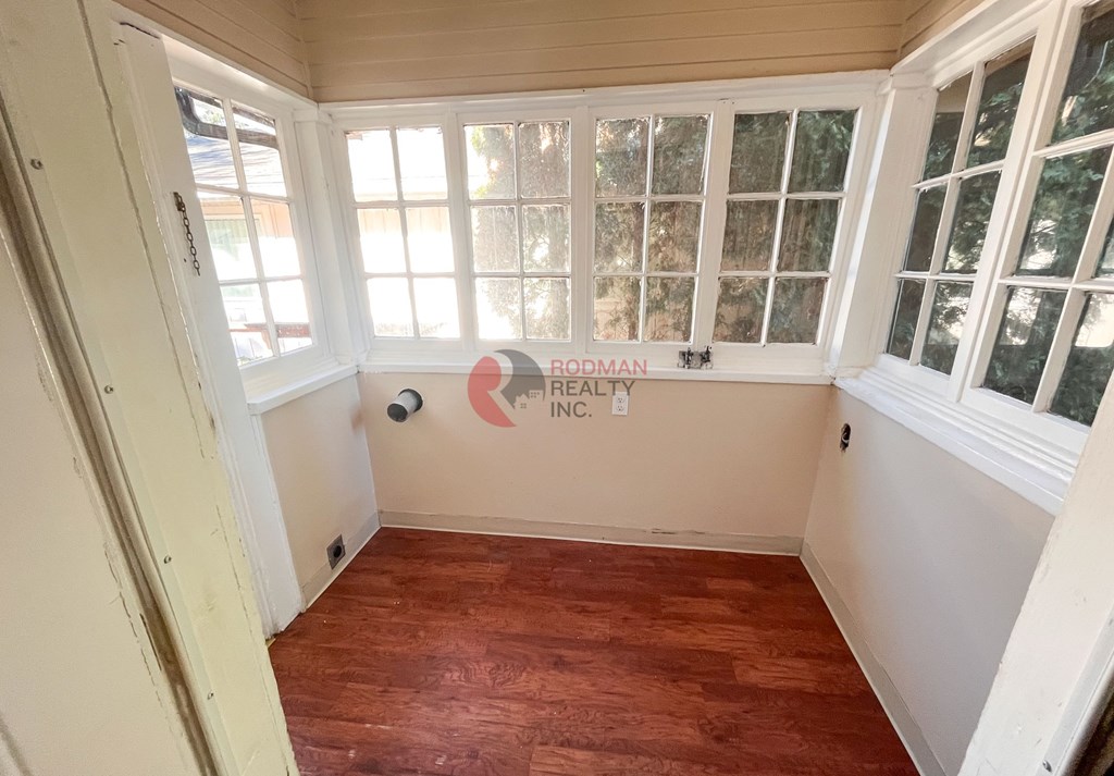 A room with wooden floors and white walls, with a window covered in white blinds.