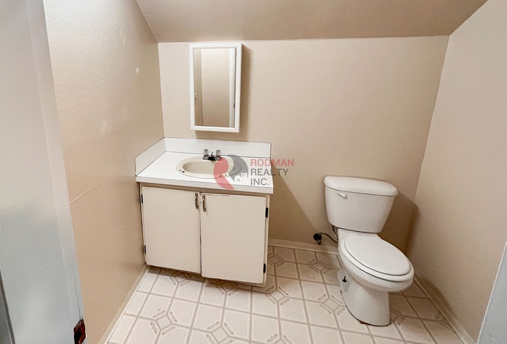 A white toilet sits next to a sink in a small bathroom.