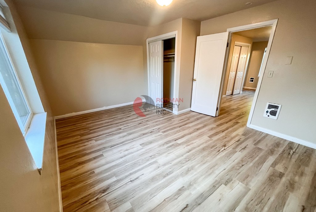 A room with wooden flooring and two open doors.