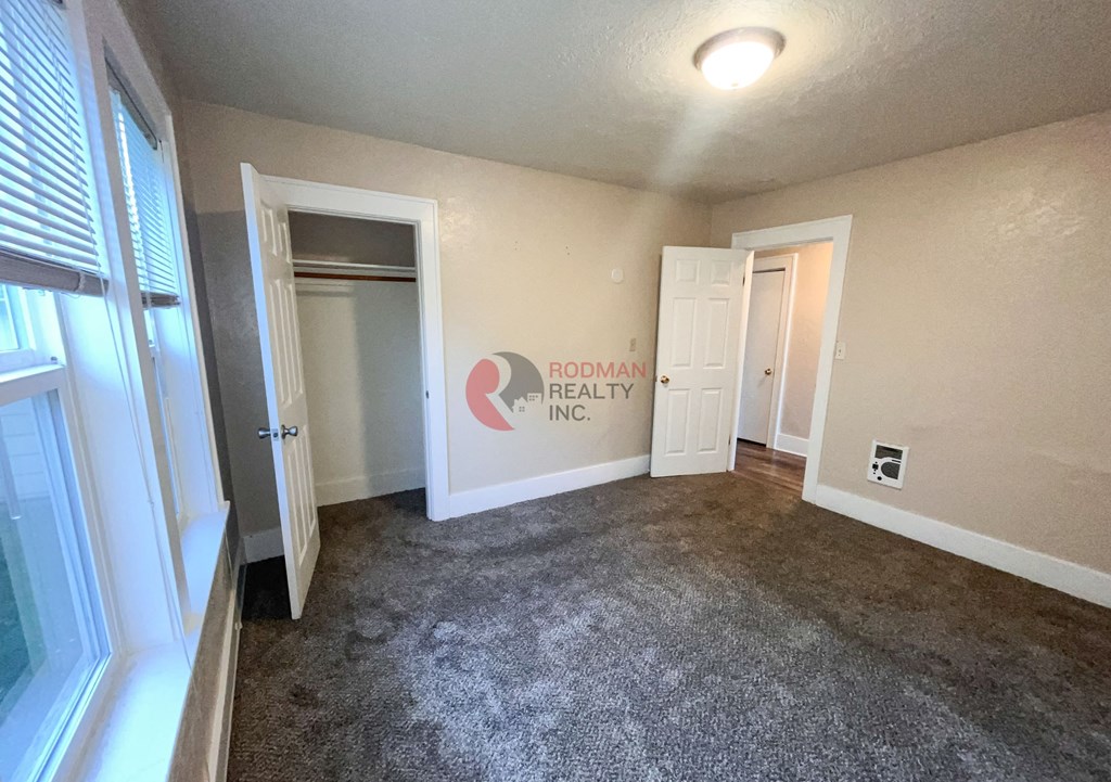 A room with carpet flooring and a window with blinds.