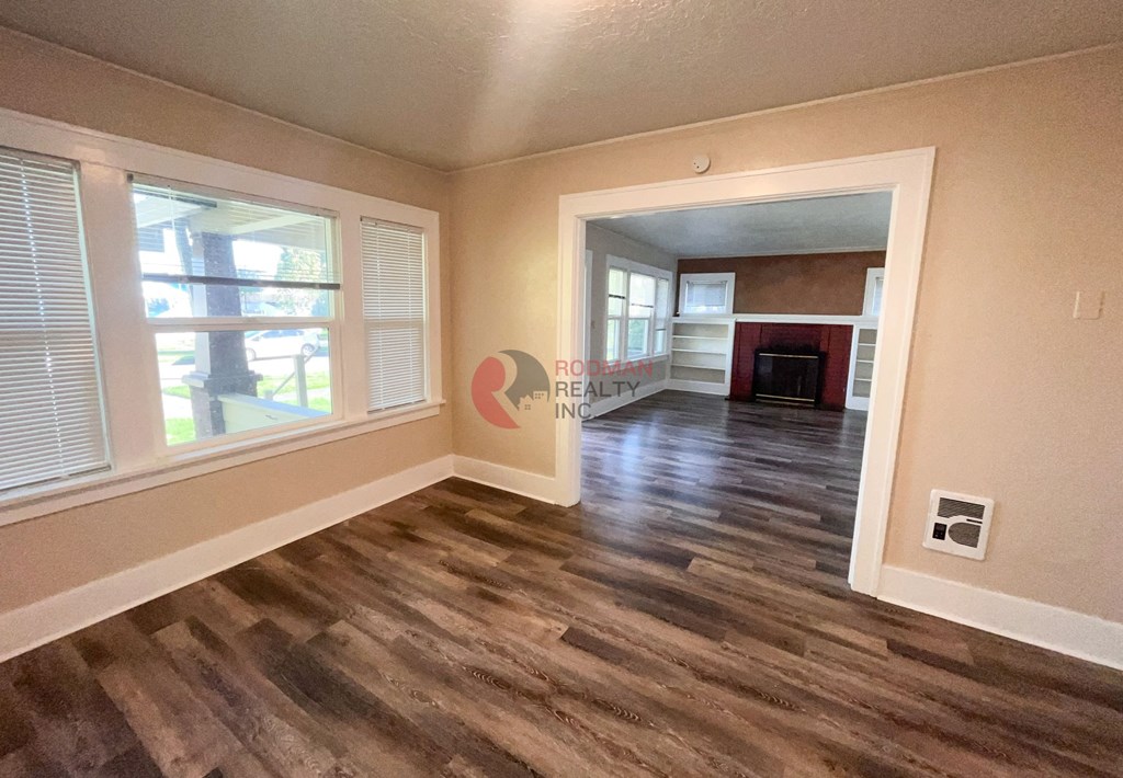 A room with wooden flooring and a window with blinds.