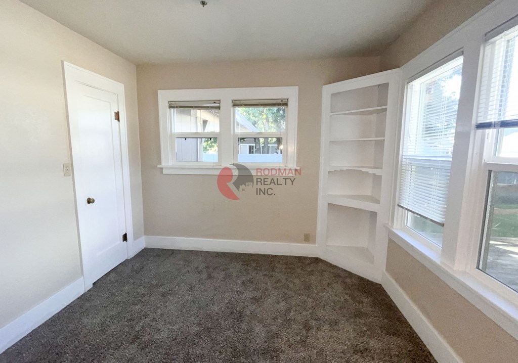 A room with a carpeted floor and a window with blinds.
