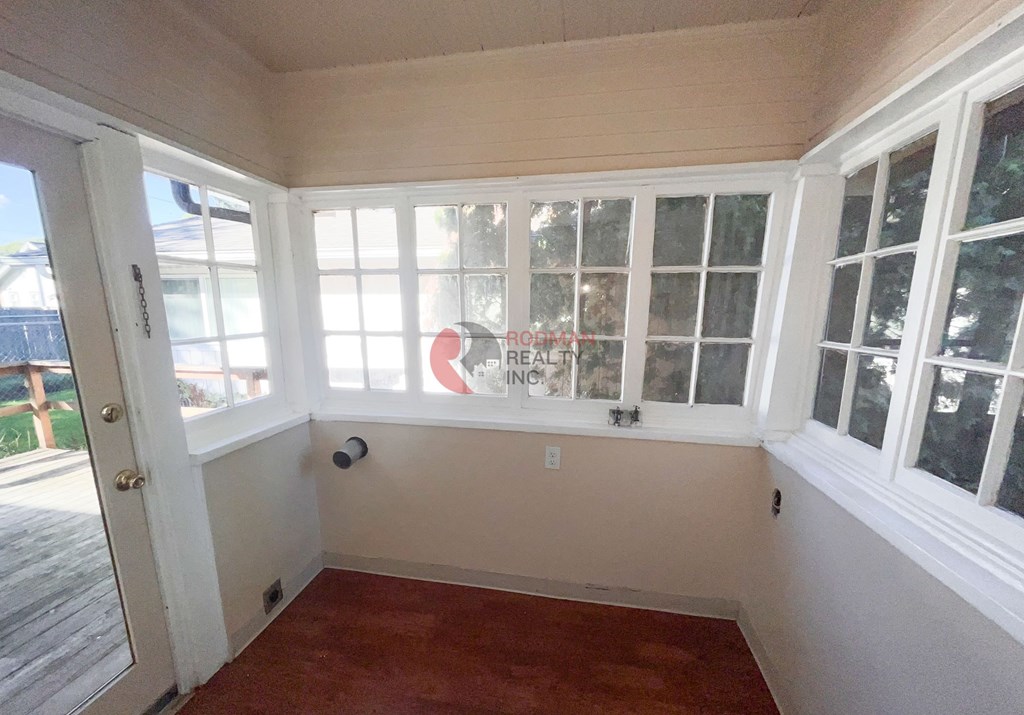 A sunroom with a red carpet and white walls.