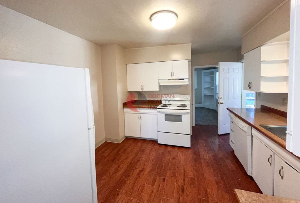 A kitchen with white cabinets and a wooden floor.