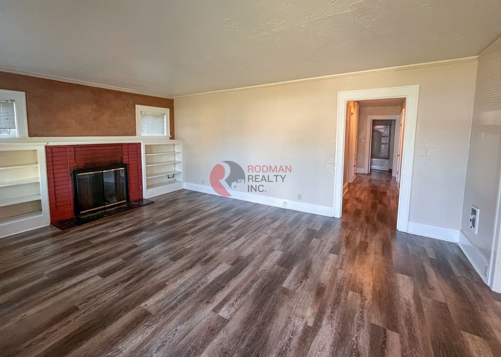 A room with a fireplace and a sign that says "Rodman Realty Inc.".